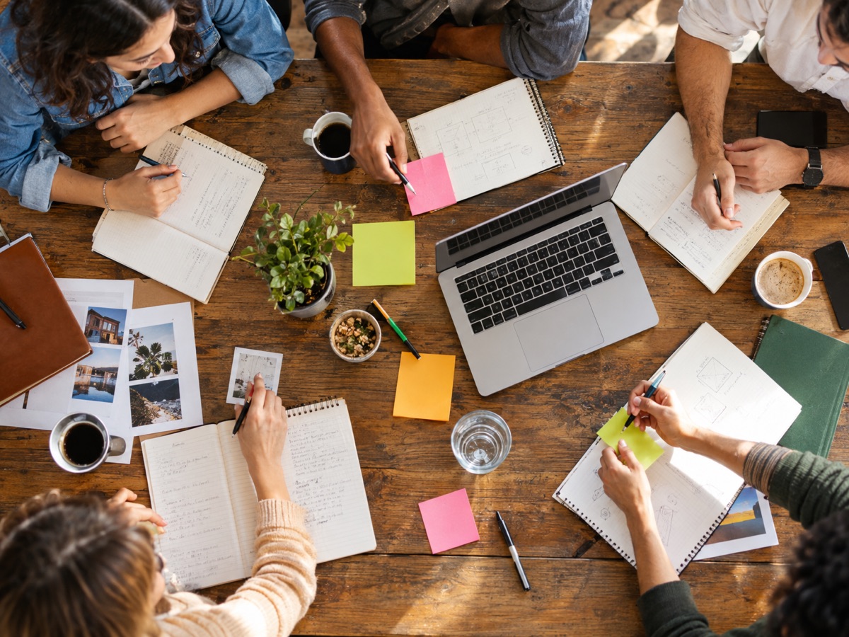 A team workshop around a table of notebooks and sticky notes